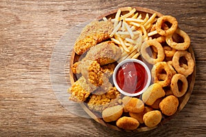 Fast food meals : onion rings, french fries, chicken nuggets and fried chicken, top view