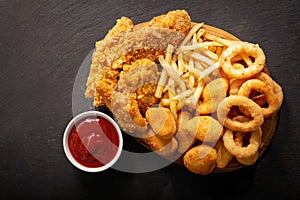 Fast food meals : onion rings, french fries, chicken nuggets and fried chicken, top view