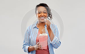 Happy african american woman eating popcorn