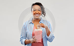 Happy african american woman eating popcorn