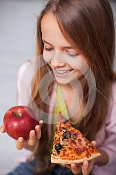 Fast food snack or fruits snack - smiling girl pondering eating both