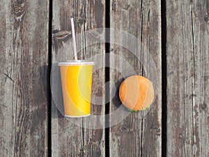 Fast food and unhealthy eating concept - juice cup with hamburger on a wooden table background