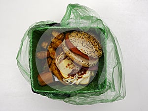 Fast food waste in a biodegradable garbage bag on a white