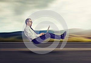 Fast internet concept. Levitating business man on road using laptop computer