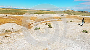 Fast motion tracking view Young pretty caucasian woman walks in real time on mud volcanoes