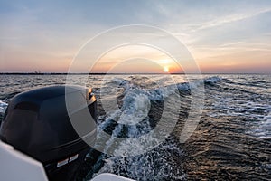 Fast motorboat ride on sea at sunset
