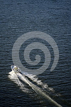 Fast motorboat rushes through the dark water of the river leaving frothy plume