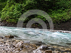 A fast mountain stream foams, meeting both stones and rocks on its way.