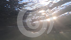 Fast movement of water with moving rays of sun on surface of water and in water.