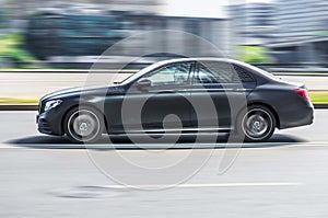 fast moving matte black car with motion blur effect. overspeed concept. mercedes benz W213 e-class auto goes fast on the road