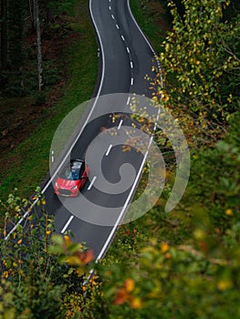 Fast moving red sport car with motion blur effect. Transport on a forest road in summer. Top view from above.