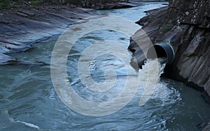 Water flowing through culvert pipe into natural river stream