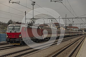 Rýchly osobný vlak s červenou modernou električkou v stanici Ilava