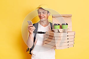 Fast service and best food delivery. Smiling Caucasian delivery man wearing cap and white t shirt holding pizza boxes and takeaway