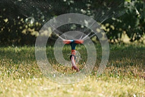 Fast spinning sprinkler head watering the grass. Splashing water from sprinkler head. Blurred motion