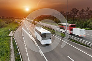Fast travel buses in motion blur on the highway at sunset
