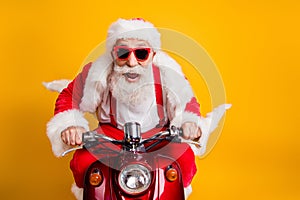 Fast x-mas traveling. Crazy funky hipster grey haired santa claus in red hat drive scooter hurry scream wear shirt