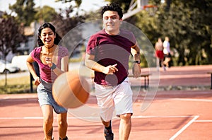 He is fast. Young couple playing basketball. Focus is on woman and man