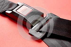 Fastened seat belt on red background with copy space, close-up