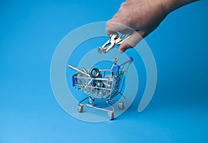 Fasteners nuts screws bolts screws in a shopping cart on a blue background and a man's hand