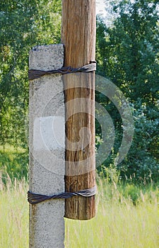 Fastening a wooden pillar to a support using wire.