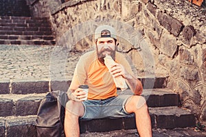 Fastfood break. Bearded man eating hot dog for meal break. Hipster tourist relaxing on stairs during rest break