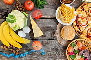 Fastfood and healthy food on old wooden background. Concept choosing correct nutrition or of junk eating.