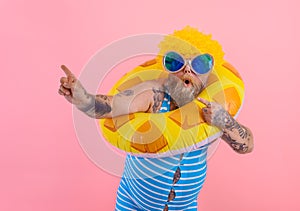 Fat amazed man with wig in head is ready to swim with a donut lifesaver