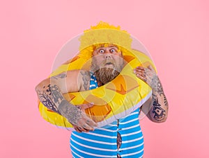 Fat amazed man with wig in head is ready to swim with a donut lifesaver