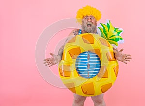 Fat amazed man with wig in head is ready to swim with a donut lifesaver