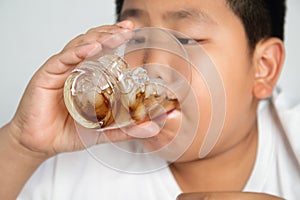 Fat Asian boy drinking soft drinks Wear a white shirt.