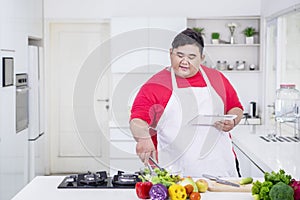 Fat Asian man demonstrating how to cook salads photo