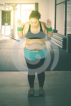 Fat Asian woman measuring her weight in a gym