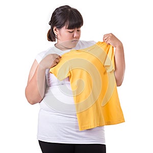 Fat asian woman trying to wear small size of yellow t-shirt isolated on white. Fat and Healthcare concept