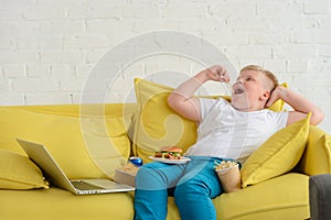 Fat boy eating French fries, burger, chips and drinking cola