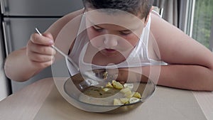 Fat boy eating soup. improper diet problems with excessive weight in children. concept of sedentary lifestyle.