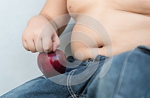 Fat boy pick up red apple , as a concept of diet.