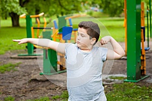 Fat boy shows his muscles in background of exercise equipment