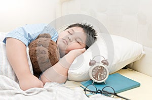 Fat boy sleep and hug teddy bear on bed