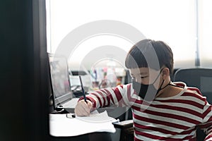 A fat boy is studying online with a tablet and a book at his mother`s office