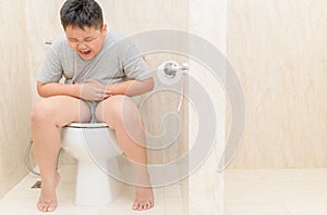 Tuk chlapec trpět a sedět v záchod 