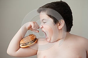 Fat boy wants to eat burger that lies on biceps
