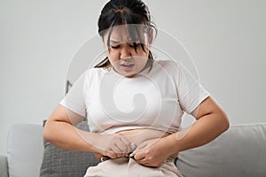 Fat chubby woman trying to wear tight pants, overweight, weight gain, Healthy and medical concept