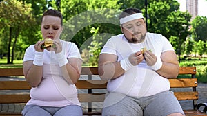 Fat couple eating burgers, feeling guilty for stopping diet, fast food addicted