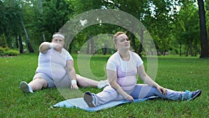 Fat couple having workouts in park together, beginners in weight loss program