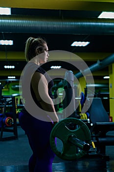 Fat European woman is engaged in fitness with a barbell in the gym. A fat girl does deadlift.