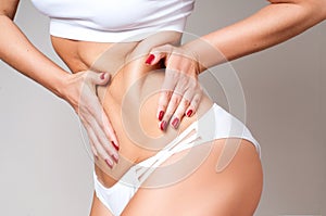 Fat female belly, woman holding her skin for cellulite check.