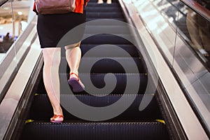 Fat female body with cellulite step up on the escalator, overweight legs on escalator background.