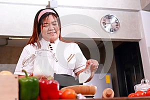 Fat female chef in white chef coat prepares dough for bakery or pizza.
