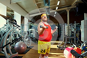 Fat funny man with dumbbells in the gym